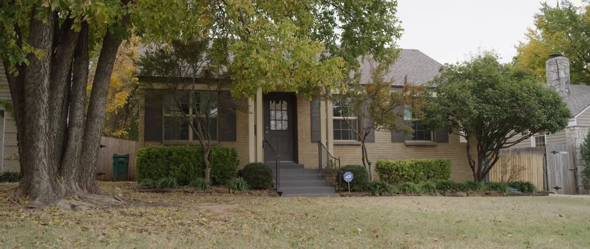 Tree branches are blowing in the wind outside a house during the day