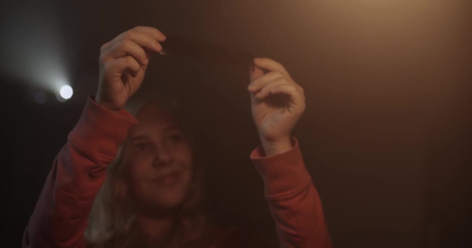 A woman holds a photo negative strip up to the light