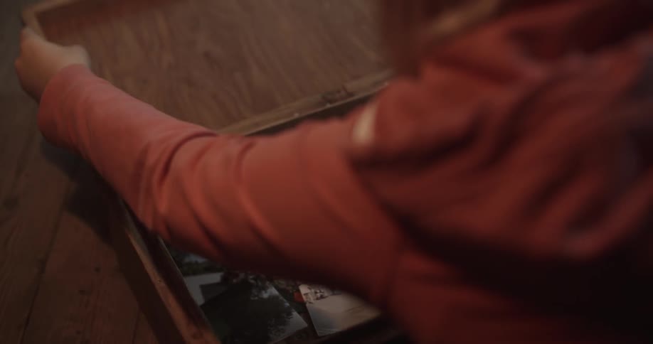 A woman is opening a chest full of photographs