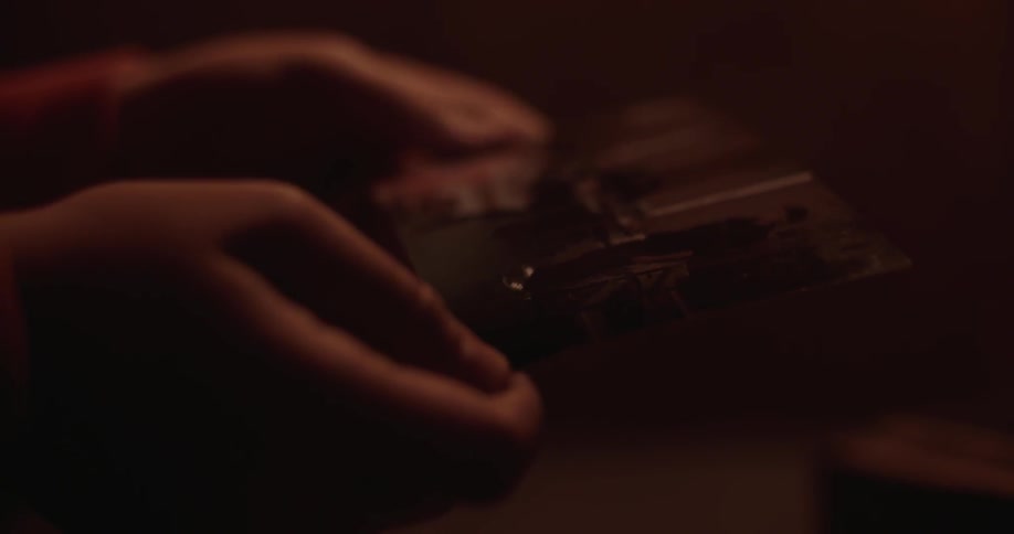 A person is examining a photograph in a dark room