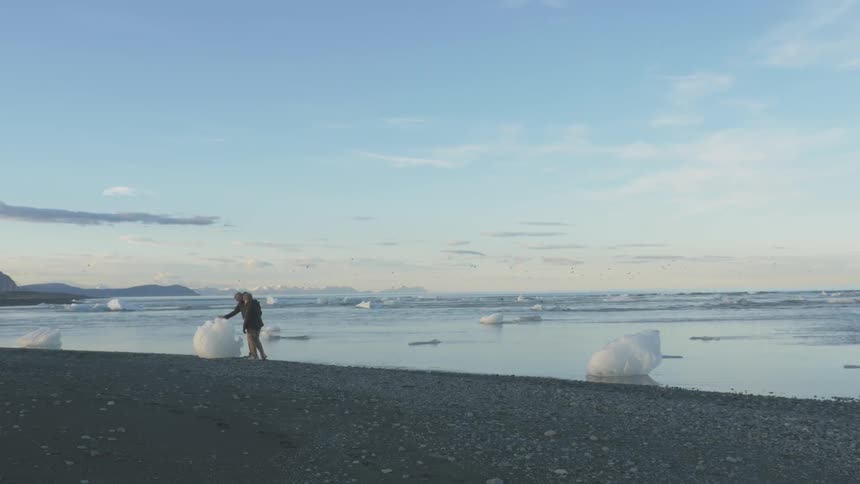 People walking from a ocean with large pieces of ice all over