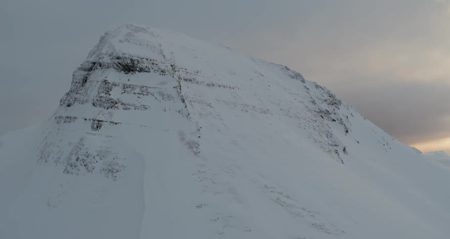 The sun sets behind a snowy mountain peak