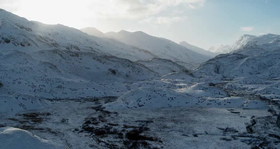 The sun is shining over a ridge in a mountain range in winter