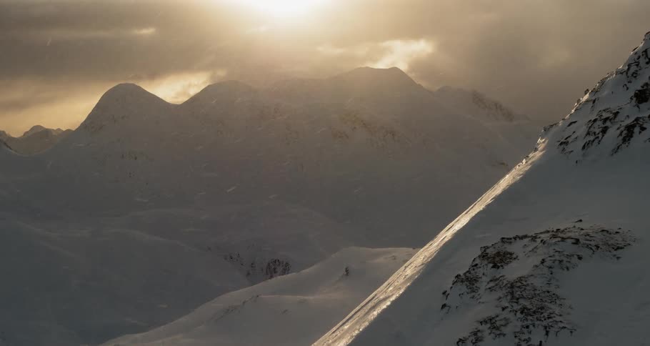 Flying by beautiful snowy mountains at sunset