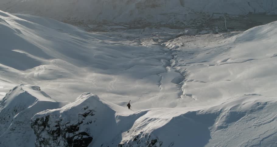 A man is walking to the top of a snow covered mountain