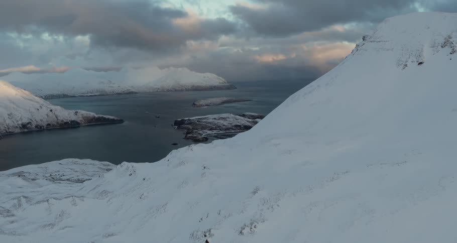 A snow covered mountain is next to an ocean