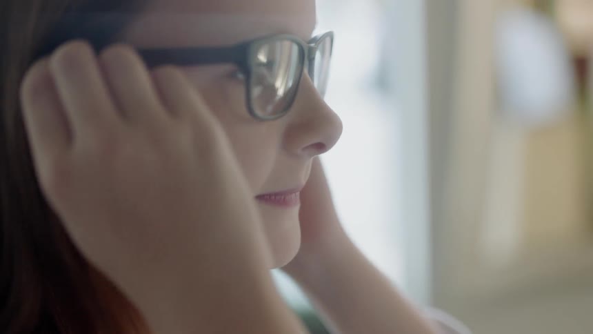 A girl is trying on a pair of eyeglasses during the day