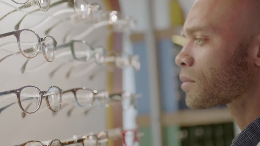 Man looking at a large display of eyeglass frames in a store