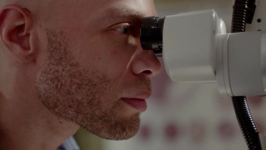 A man is looking through a microscope
