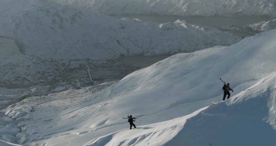 Two people hike in snow covered mountains