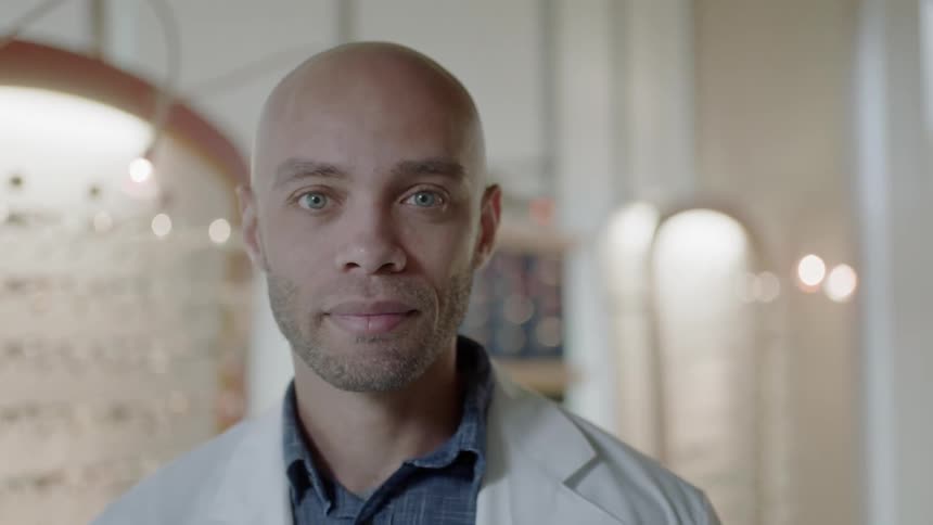An optometrist is looking straight ahead as he stands in his office