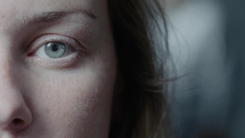 A woman opens her eye and stares forward