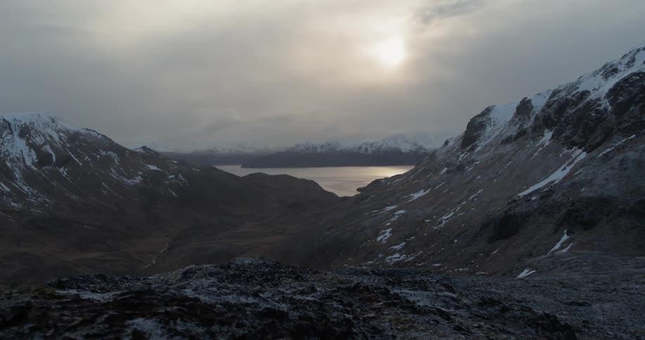 Snowy mountains surround a lake at sunset