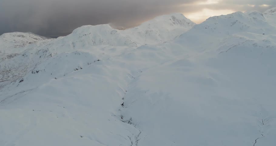 Snow covers a mountainside at sunset