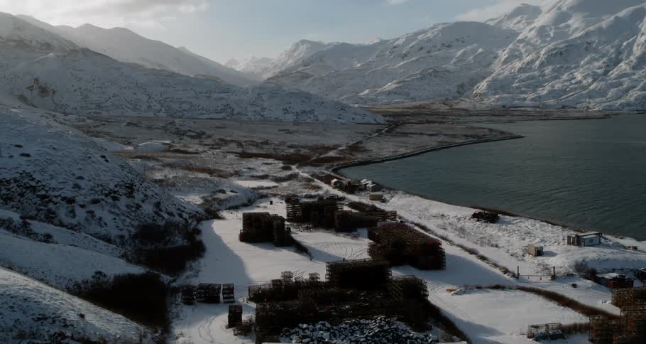 Crab pots sit stacked and idle on a shoreline in winter