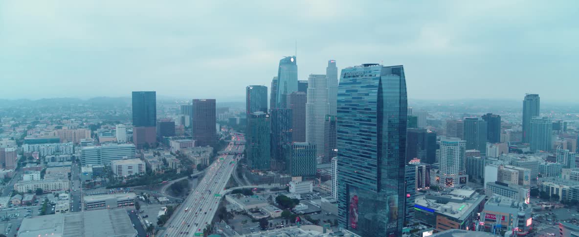 Cars travel on a city highway past skyscrapers