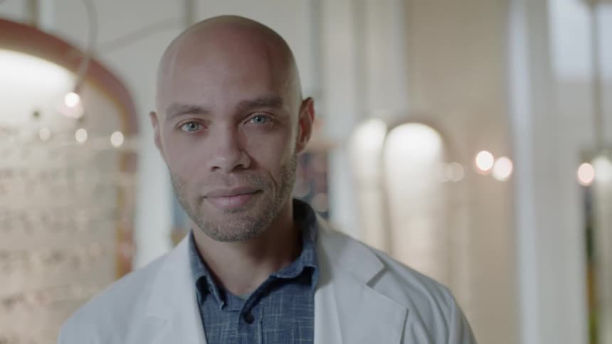 An optometrist stands in front of a display of eyeglasses
