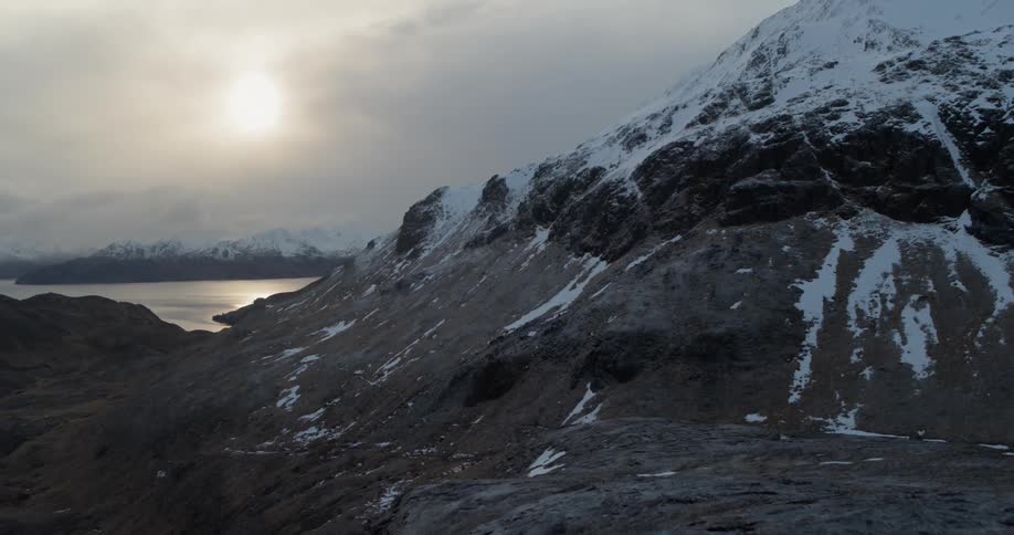 The sun is shining through clouds over a mountain range during the day