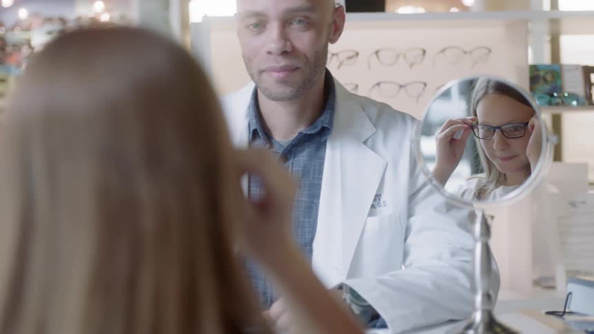Woman tries on glasses while a man watches
