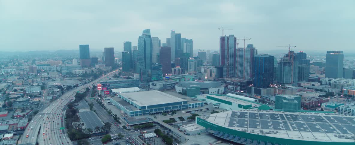 Vehicles are traveling on a freeway outside a city on a cloudy day