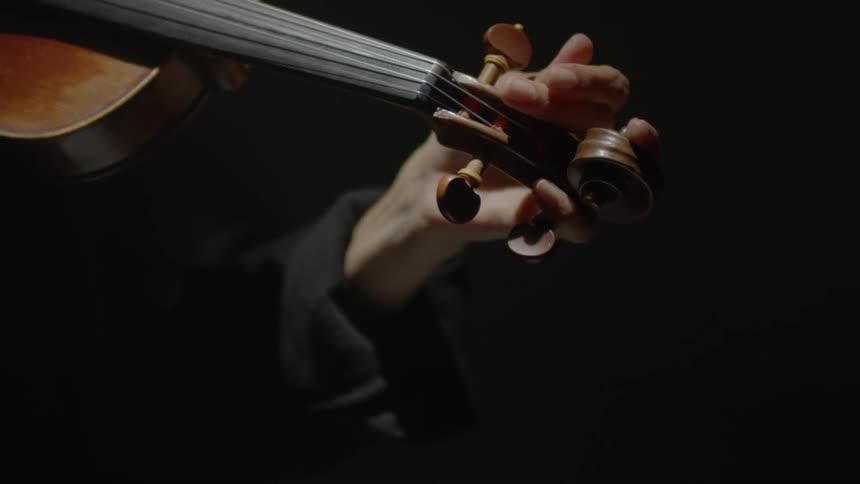 A woman is tuning her violin