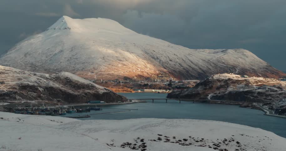 Bridge spanning a body of water surrounded by snow-covered hills