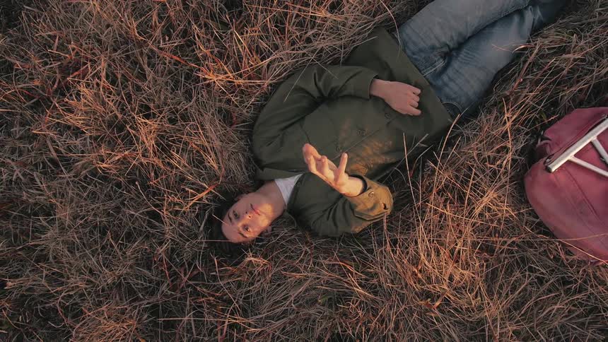 A man lays in a grassy field