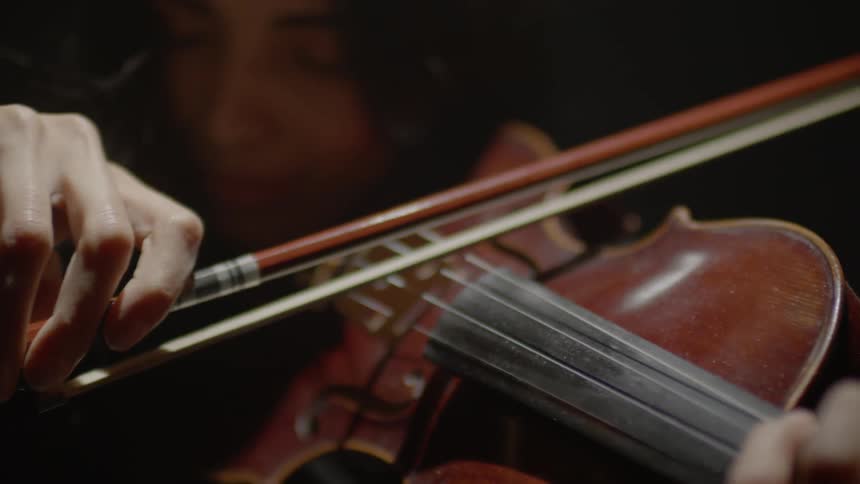 A woman is playing the violin in the dark