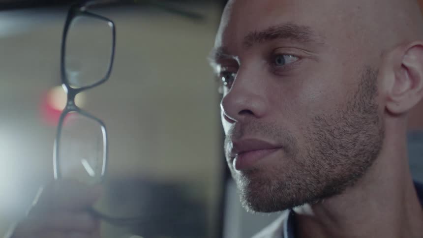 A man is inspecting a pair of eyeglasses
