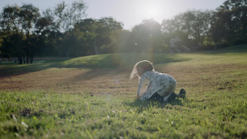 Several children play in a grassy field on a sunny day