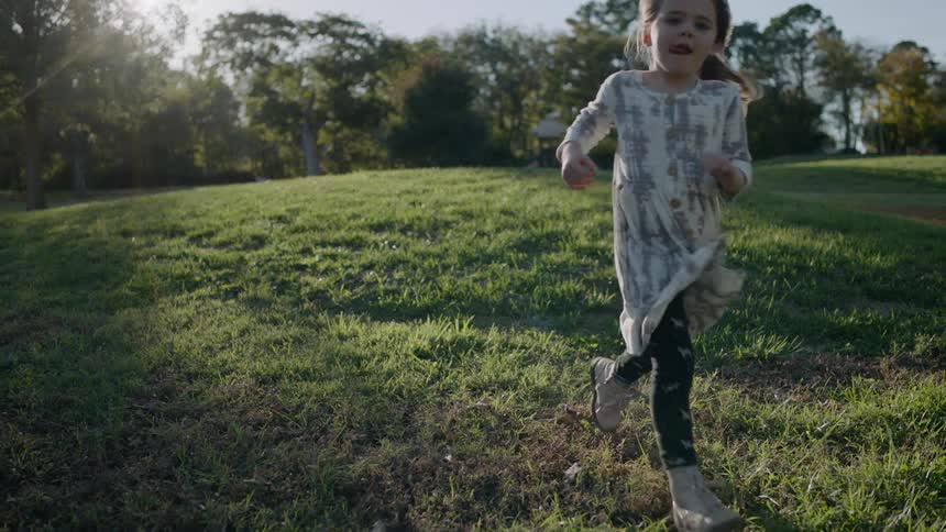 A young girl runs on grass