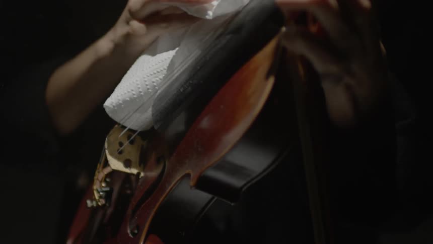 Person wipes off violin strings with paper towel