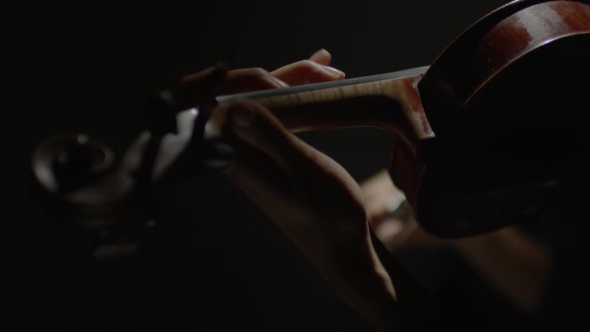 A close up of someone holding and playing a violin