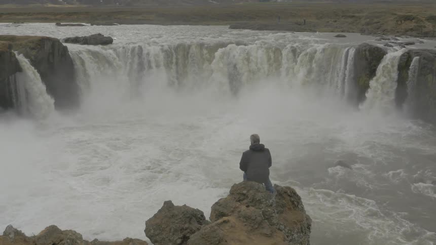 A man is watching a waterfall