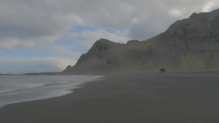 Landscape view of people walking on the shoreline on a cloudy day