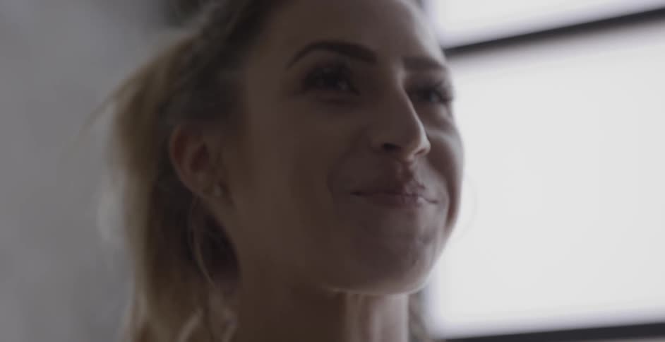 A woman smiles while drinking a protein shake