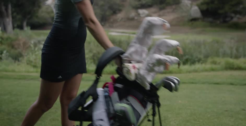 A woman puts her golf bag down on the green