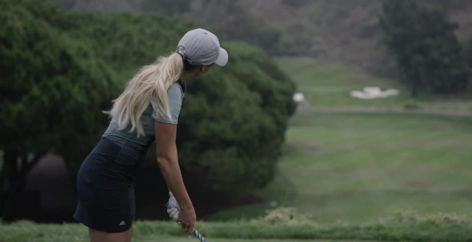 A woman golfs on a golf course