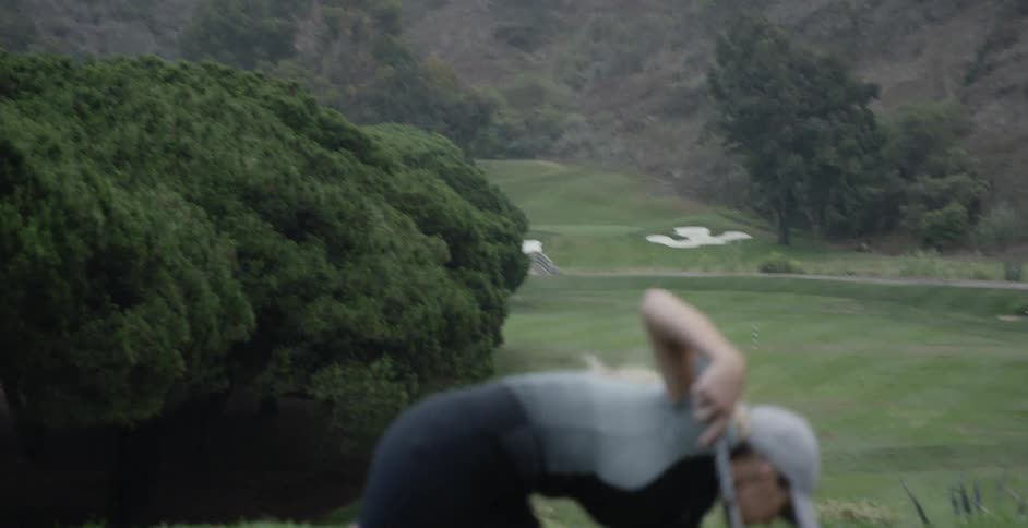 A woman is picking her tee up off the green after taking a golf shot