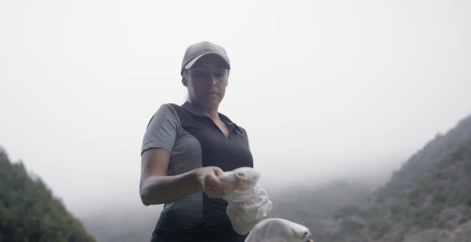A woman carrying a golf bag puts it down and takes out a club