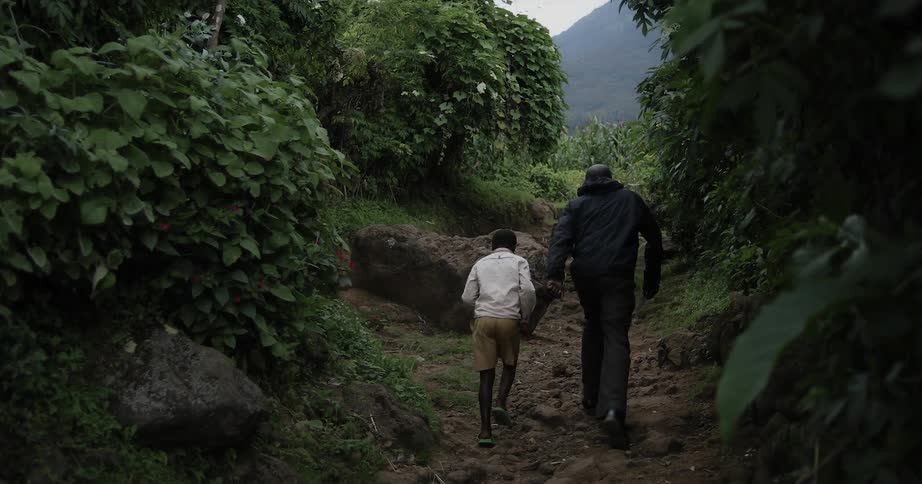 Man and child walk on a path in a wooded area