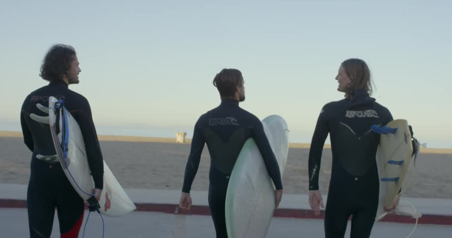 Surfers walk on a beach with surfboards