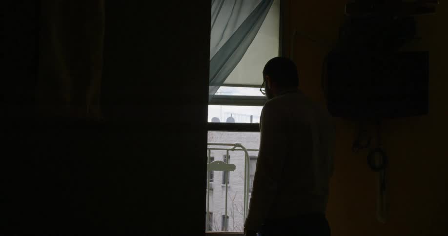 Woman looks out bedroom window