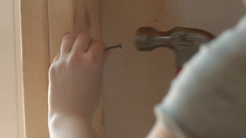 Someone is hammering a nail into a board