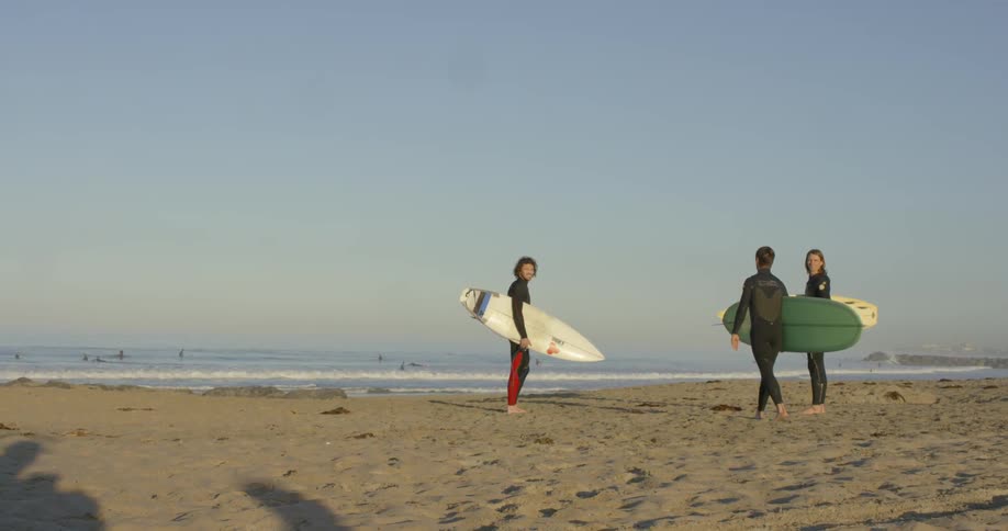 A man turns from the ocean holding a surfboard