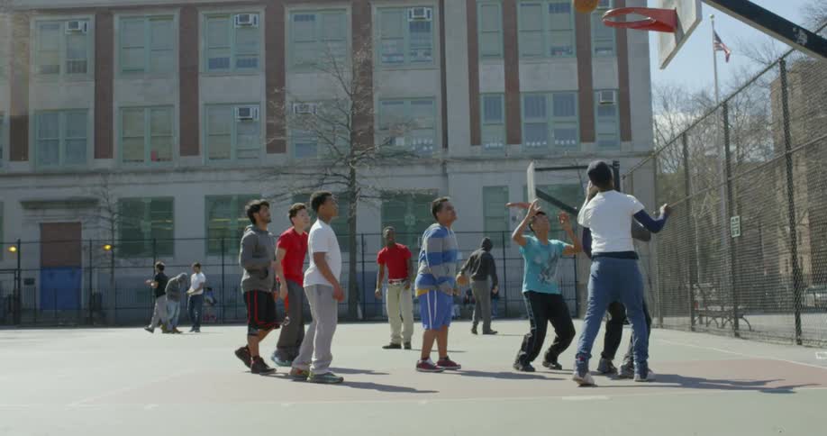 A group of kids are playing basketball outdoors