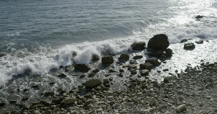 Waves are crashing over rocks on a beach