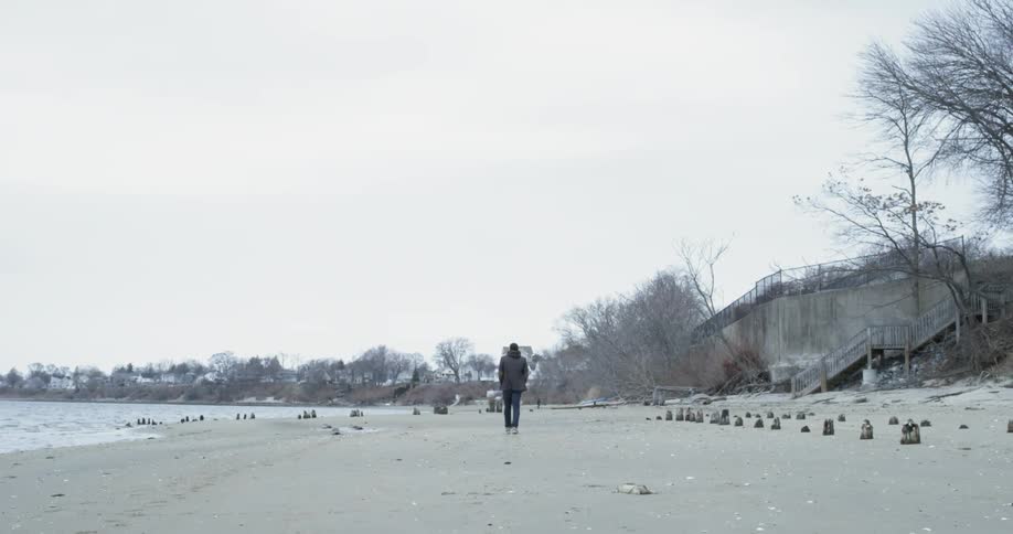 A man is walking along the sand by the water