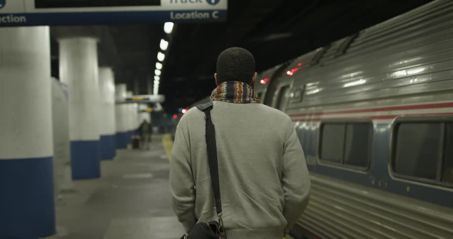 A man is walking on a train platform in a station