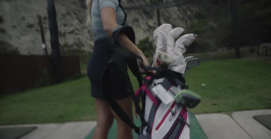 A woman golfs at a driving range